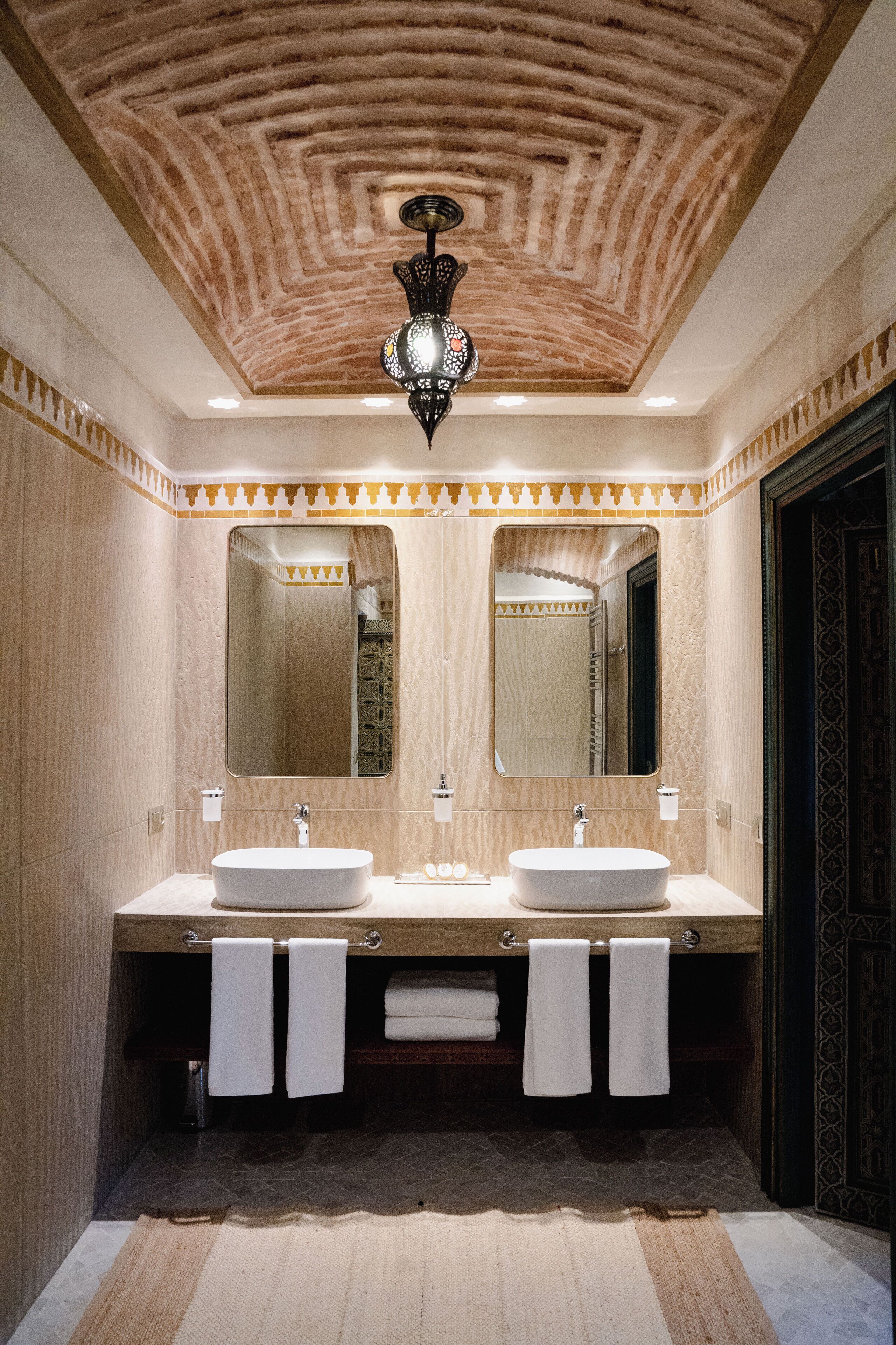 A bathroom with two sinks, a large mirror, and a patterned ceiling.