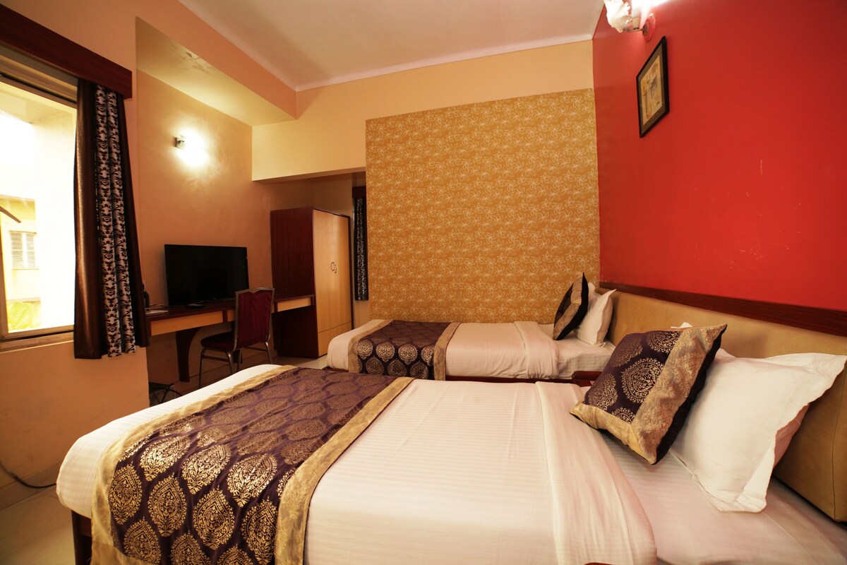 A hotel room with two beds, a desk, and a television.