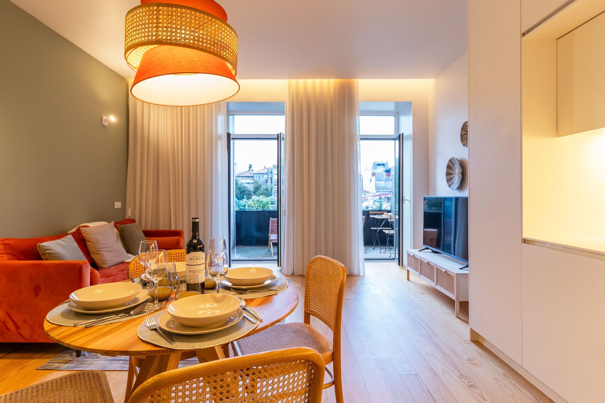 A dining area with a table set for four, a red sofa, and a view of the outdoors.