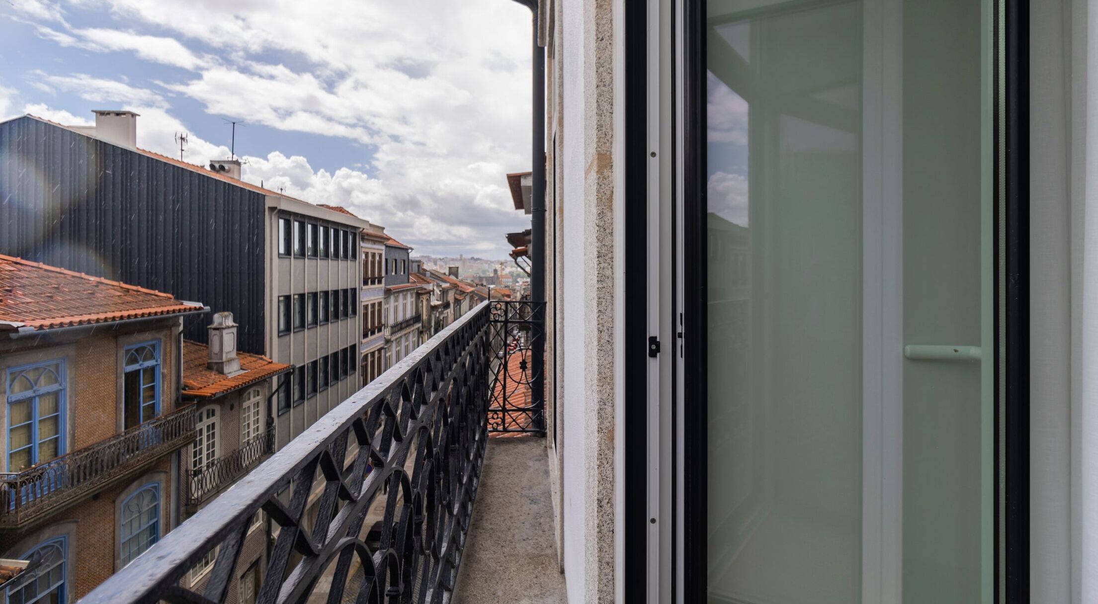 Un balcón con barandilla de metal que da a una hilera de edificios con tejados rojos.