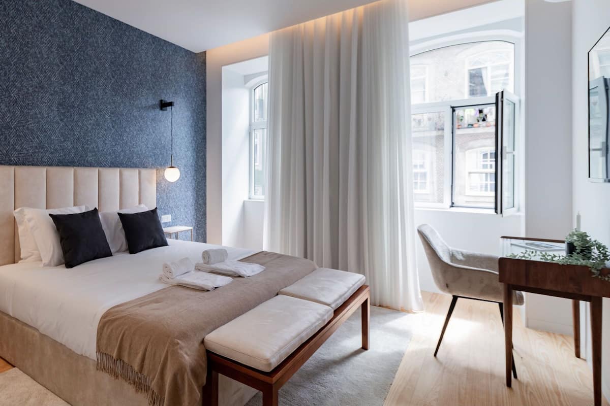 Un dormitorio moderno con una cama grande, mesitas de noche, un escritorio y una silla.