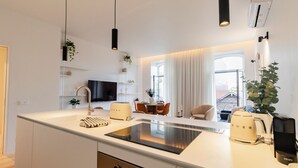 A modern kitchen with a central island, built-in appliances, and a dining area with a table and chairs. - Almada 551 by LovelyStay (Porto)