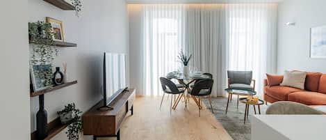Un soggiorno moderno con televisione, tavolo da pranzo e sedie, un divano e un tavolino.