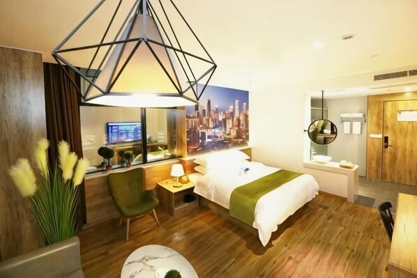 A hotel room with a bed, desk, chair, lamp, and a cityscape view.