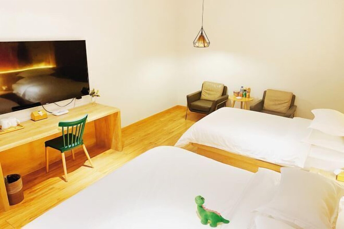 Ein Hotelzimmer mit Fernseher, Schreibtisch, zwei Stühlen, einem Bett und einem kleinen Tisch.