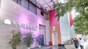 A hotel entrance with a modern design, featuring a prominent sign, a staircase, and potted plants. - Jiejiao 33 Qinglv Hotel (Chongqing)