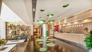A hotel lobby with a reception desk, seating area, and a large bookshelf. - Jiejiao 33 Qinglv Hotel (Chongqing)