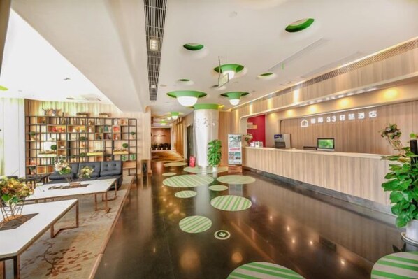 A hotel lobby with a reception desk, seating area, and a large open space with a polished floor. - Jiejiao 33 Qinglv Hotel (Chongqing)