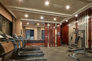 A gym with treadmills, weight machines, and a mirrored wall. - Jiejiao 33 Qinglv Hotel (Chongqing)
