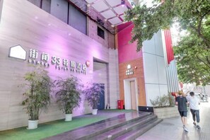 A hotel entrance with a sign, potted plants, and a staircase leading to the entrance. - Jiejiao 33 Qinglv Hotel (Chongqing)