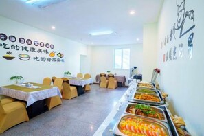 A dining area with tables and chairs, buffet with various food items, and wall decorations. - General Fenghua (Lijiang) Travel Center (Lijiang)