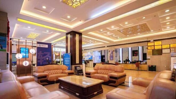 A spacious lobby with leather sofas and a central coffee table, featuring a reception desk and framed certificates on the wall. - General Fenghua (Lijiang) Travel Center (Lijiang)