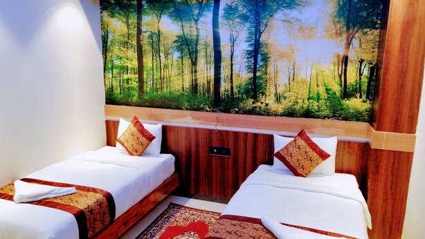 A hotel room with two beds, a large forest mural on the wall, and a wooden headboard. - Hotel Red Crown Pvt Ltd-Bardibas (Bardibas)
