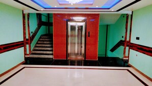 A modern lobby with a central elevator, a staircase, and a chandelier. - Hotel Red Crown Pvt Ltd-Bardibas (Bardibas)