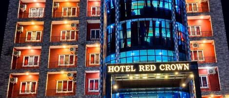 A multi-story hotel with a prominent 'HOTEL RED CROWN' sign, featuring a modern design with glass and metal elements.
