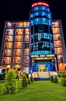 Un hotel de varios pisos con un llamativo letrero 'HOTEL RED CROWN', que presenta un diseño moderno con elementos de vidrio y metal.