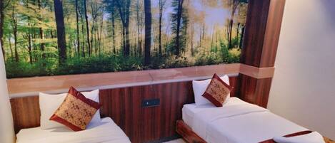 Una habitación con dos camas, cada una con cabecero de madera y un amplio mural de un bosque en la pared superior.