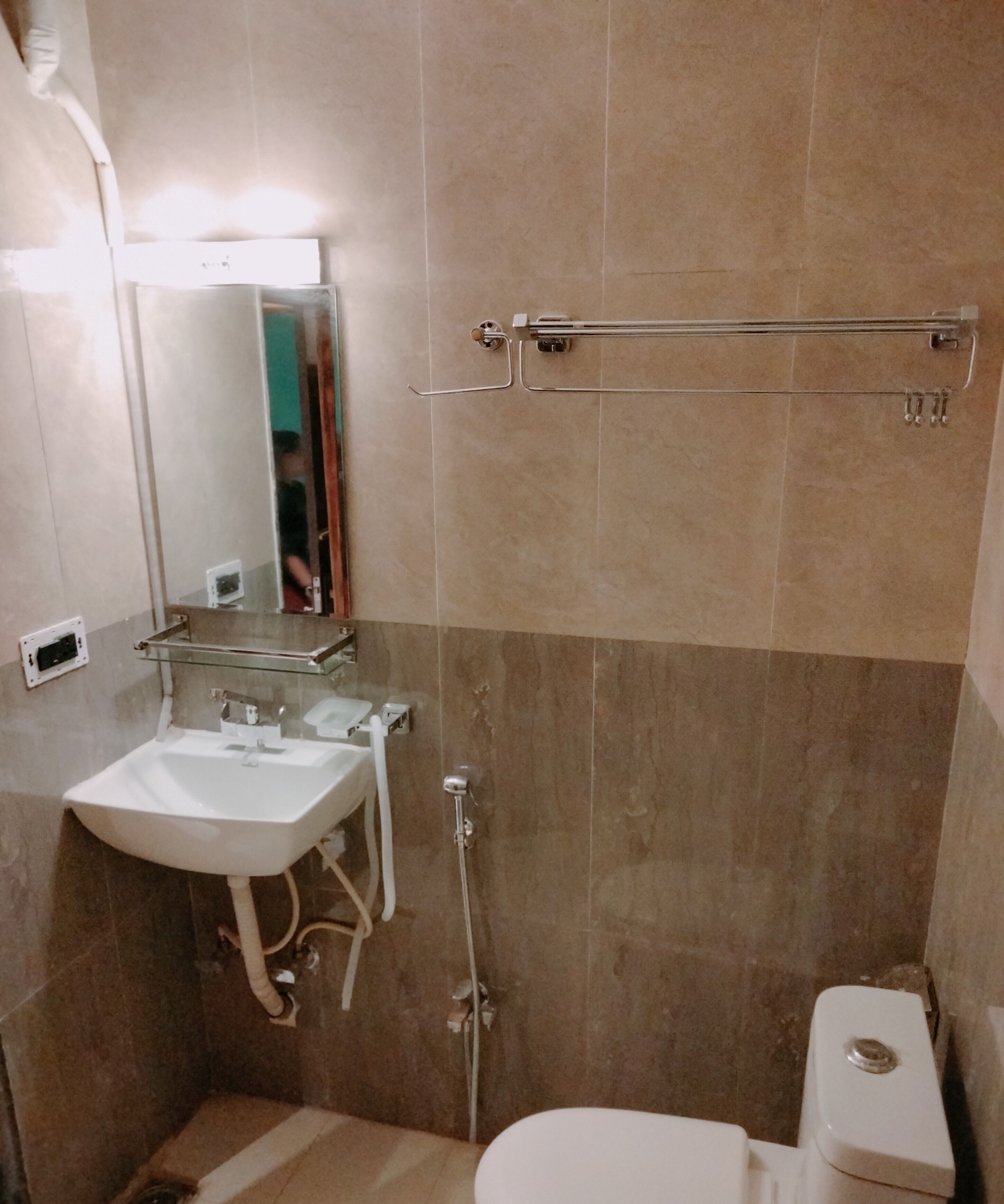 Un baño con lavamanos, espejo, toallero, ducha e inodoro.