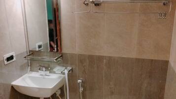 Un baño con lavamanos, espejo, toallero, ducha e inodoro.