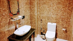 A bathroom with a marble sink, a toilet, and a mirror with a decorative frame. - Hotel Red Crown Pvt Ltd-Bardibas (Bardibas)