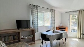 Ett rum med en säng, en tv, ett matbord med stolar och en öppen spis.