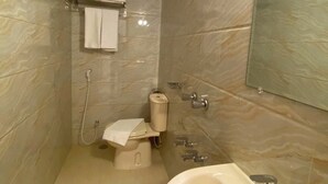 A modern bathroom with a toilet, bidet, sink, and mirror. - Crown Palace Residence (Dhaka)