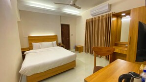 A hotel room with a wooden bed, a desk with a chair, a television, and an air conditioning unit. - Crown Palace Residence (Dhaka)