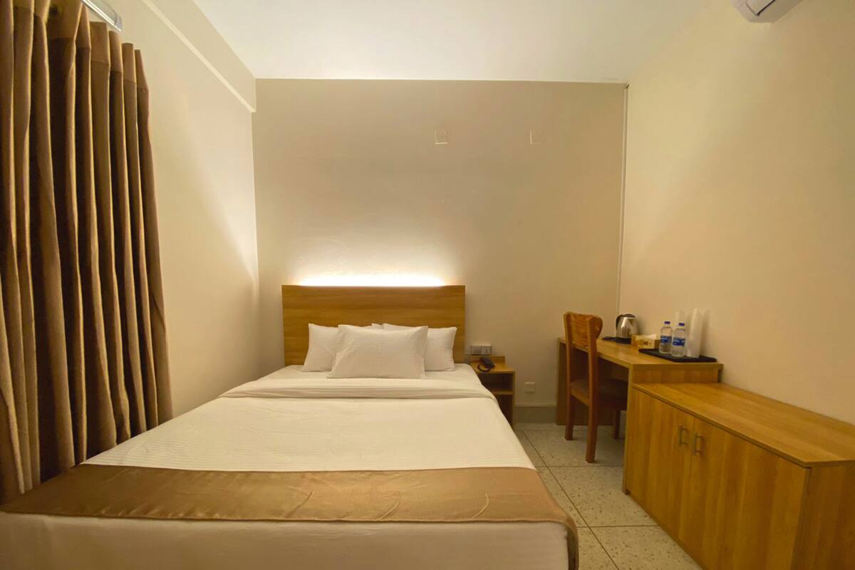A hotel room with a bed, a desk, a chair, and a cabinet.