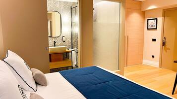 Un dormitorio con cama, un baño con lavamanos y ducha.