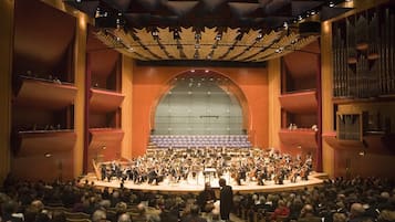 Une salle de concert avec un orchestre sur scène, un public au premier plan et un grand orgue en arrière-plan.