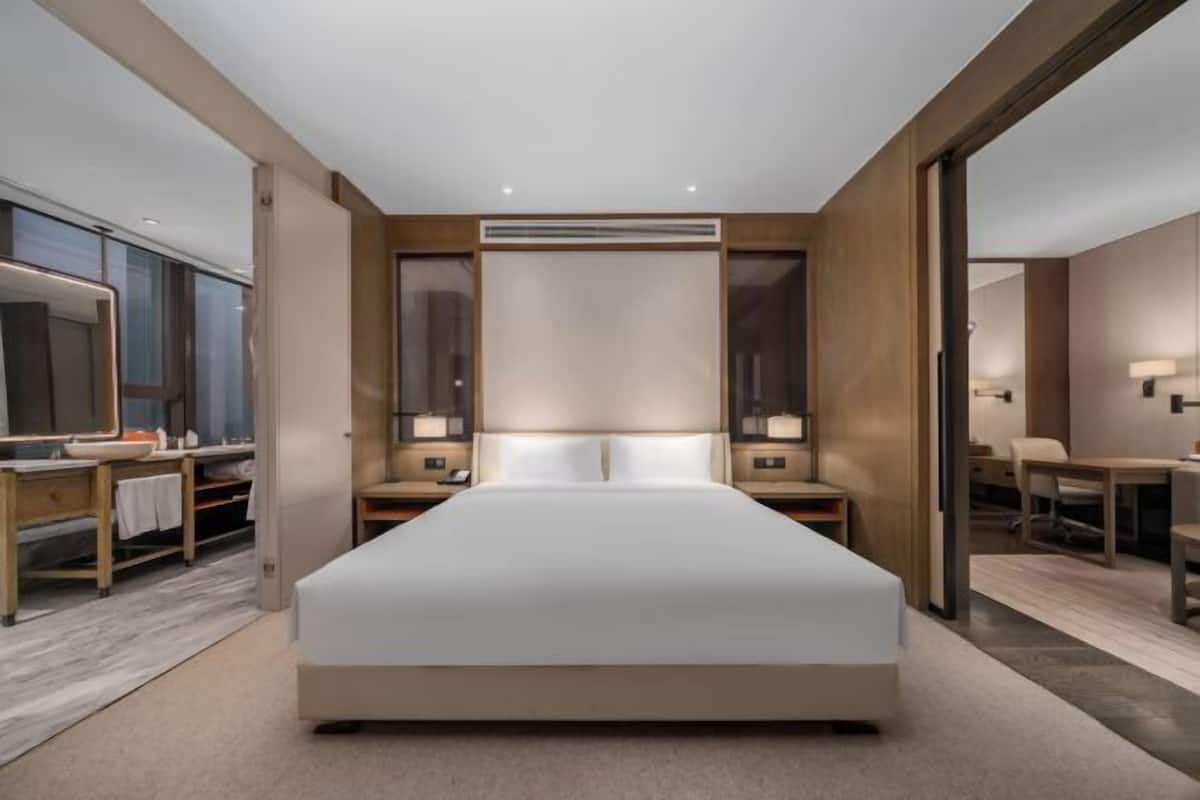 Una habitación de hotel moderna con una cama grande, mesitas de noche, un espejo y un escritorio con una silla.