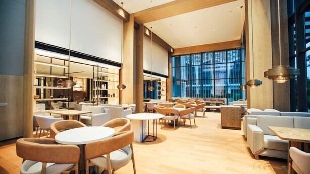 A spacious, modern lounge area with multiple seating options, including round tables and sofas, and large windows providing natural light. - Zhenhe Yiting Hotel (Ningbo)