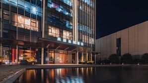A modern hotel with a reflective pool in front, large windows, and a well-lit entrance area. - Zhenhe Yiting Hotel (Ningbo)