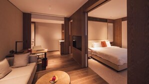 A modern hotel room with a sofa, a bed, a TV, and a small table with fruit. - Zhenhe Yiting Hotel (Ningbo)