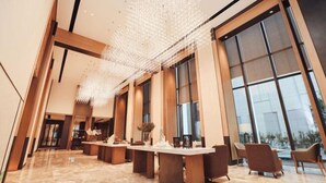 A spacious lobby with a long reception desk, large windows, and a modern chandelier. - Zhenhe Yiting Hotel (Ningbo)