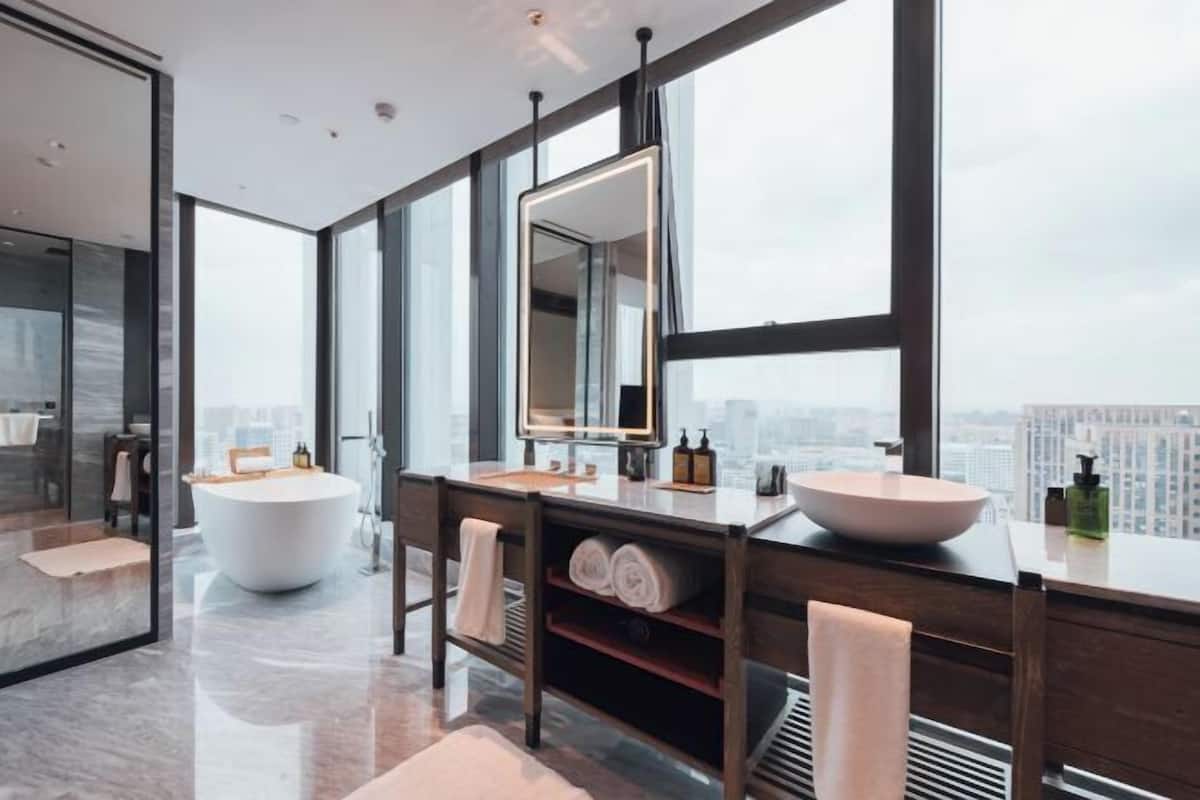 Un baño moderno con un ventanal grande, una bañera y un tocador con espejo.
