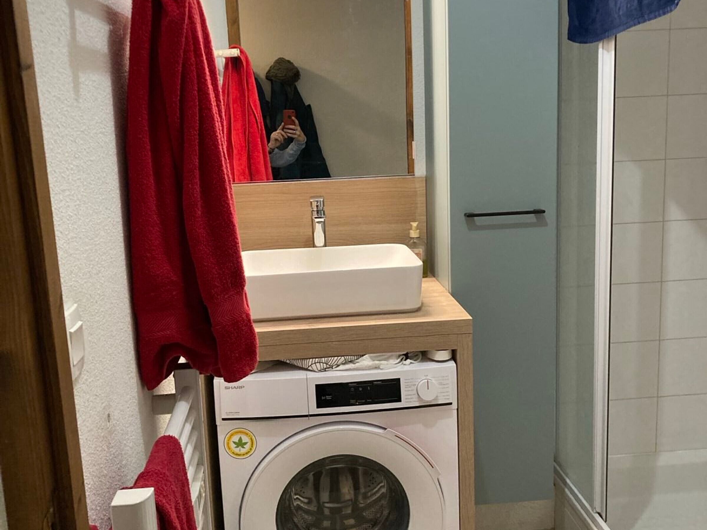 Une petite salle de bain avec un lavabo blanc, un lave-linge et un miroir au-dessus du lavabo.