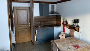 A compact kitchen with wooden cabinetry, a built-in stove, and a small refrigerator. - Duplex for 8 with WiFi, balcony and parking in Valloire (Valloire)