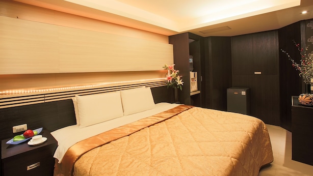 Ein Hotelzimmer mit einem großen Bett, einem Nachttisch und einem Beistelltisch mit einer Obstschale.