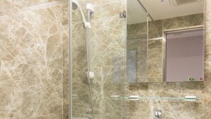 Ein modernes Badezimmer mit einer Glaskabine, einem Standwaschbecken und einem Spiegel darüber.