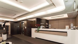 Ein moderner Hotel-Empfangsbereich mit Empfangsschalter, einer Wandtafel und einer Theke.