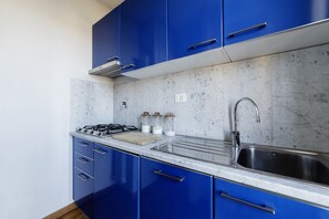 A kitchen with blue cabinets, a gas stove, a sink, and marble countertops. - GuestHost - Bright and quiet apartment of 50 square meters, can accommodate up to 4 people, located on the eighth floor of a building with elevator ( reaches the seventh floor - NOT suitable for disabled people).The property boasts an amazing view of Rom (Roma)