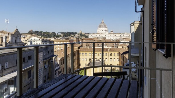 Uma varanda com vista para um horizonte urbano, incluindo um edifício com uma cúpula imponente.