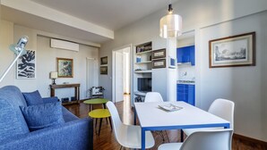 Uma sala de estar moderna com sofá, mesa de jantar e cadeiras, cozinha com armários e uma mesa de jantar com cadeiras.