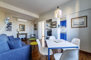 A modern living room with a sofa, dining table, and chairs, a kitchen area with cabinets, and a dining table with chairs.