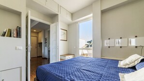 Quarto com uma cama grande, um guarda-roupa, uma escrivaninha e uma janela com vista.