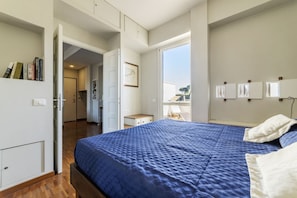 A bedroom with a large bed, a wardrobe, a desk, and a window with a view.