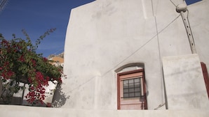 A white building with a small window and a red door. - Traditional Farmers Secret Cave #2 Santorini (Emporio)