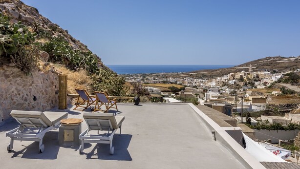 A rooftop terrace with lounge chairs and a view of a coastal town. - Traditional Farmers Secret Cave #2 Santorini (Emporio)