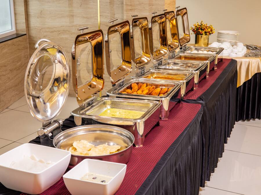 Un buffet avec plusieurs points de service où sont présentés différents plats, notamment des plateaux contenant divers mets et un assortiment de saladiers.